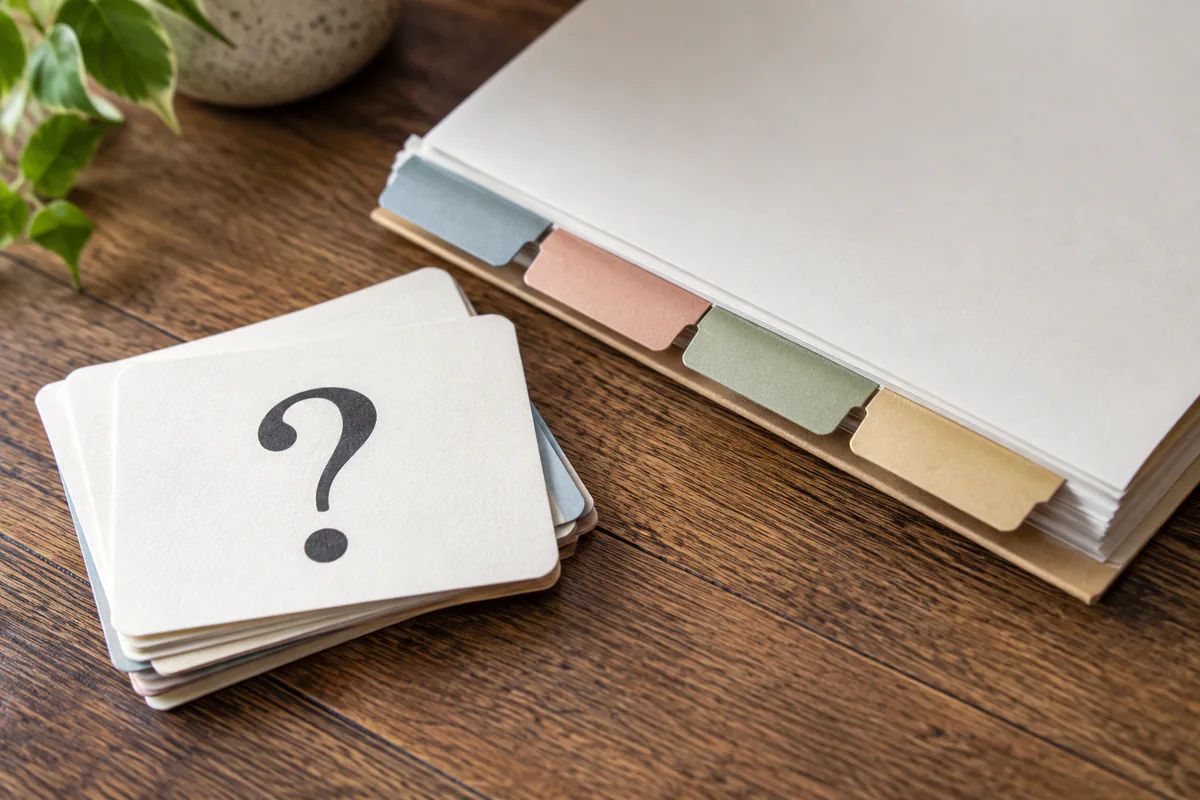A question-mark card lies beside a folder with colored tabs.